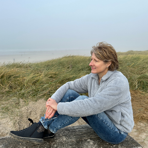 Kerstin Sommer sitzt an einer Düne an der Nordsee